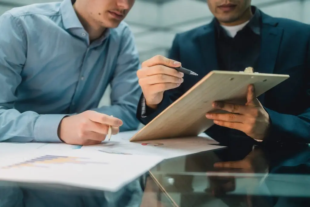 Zwei Manner unterhalten sich w&auml;hrend sie auf ein Clipboard schauen